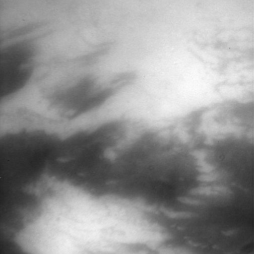 Peering through Titan thick haze, the Cassini spacecraft glimpses boundaries between bright and dark terrain on the moon trailing hemisphere. The bright terrain at bottom is in northwestern Adiri