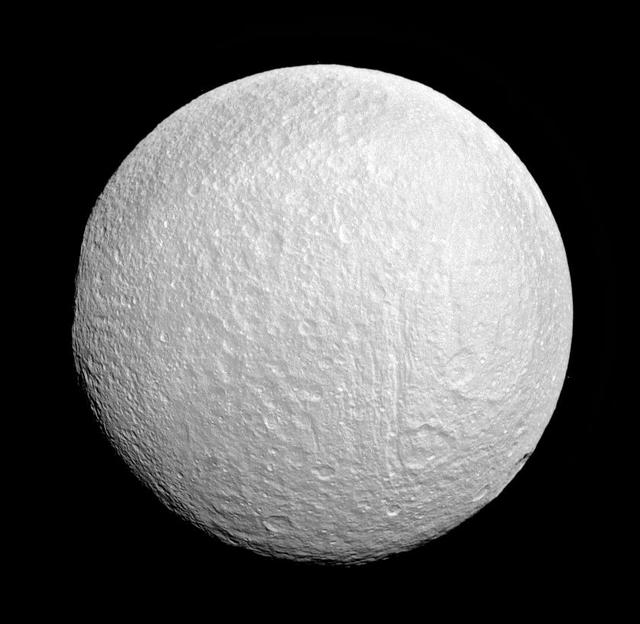 Ithaca Chasma rips across Tethys from north to south near the center of this view. The moon western limb is flattened, indicating the rim of the giant impact basin Odysseus