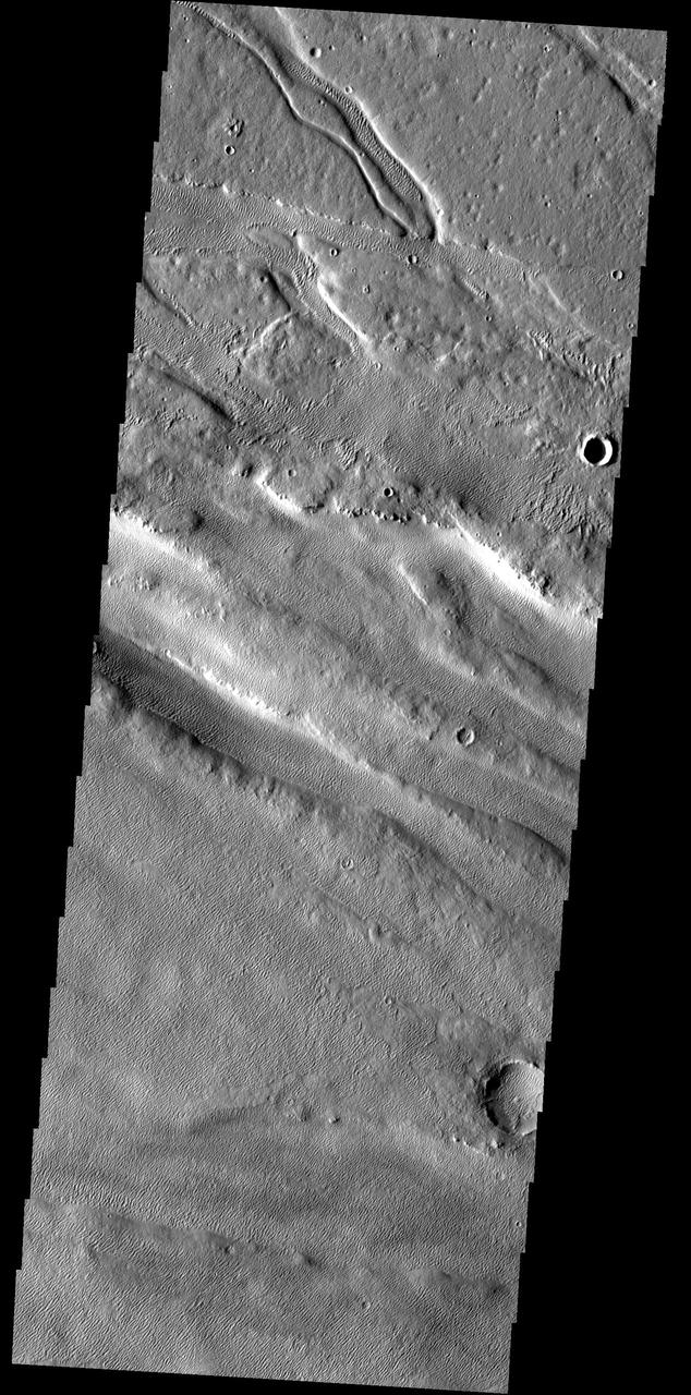 Located between Lycus Sulci and Acheron Fossae, the surface in this region has been modified by the wind. The bottom half of the image contains linear sand dunes