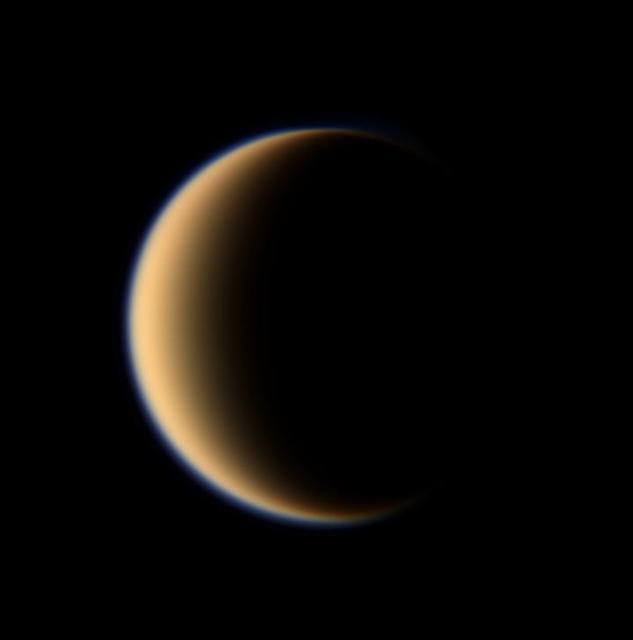 Titan hazy orange globe hangs before the Cassini spacecraft, partly illuminated -- a world with many mysteries yet to be uncovered.