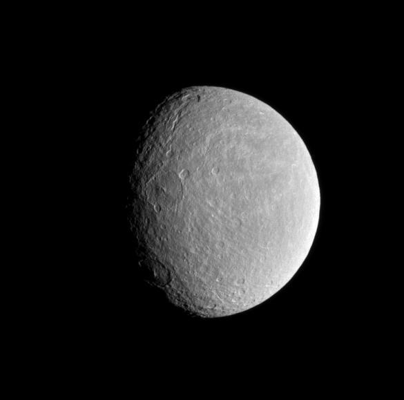 The sun low angle near the terminator highlights the topography of  craters within Rhea wispy terrain