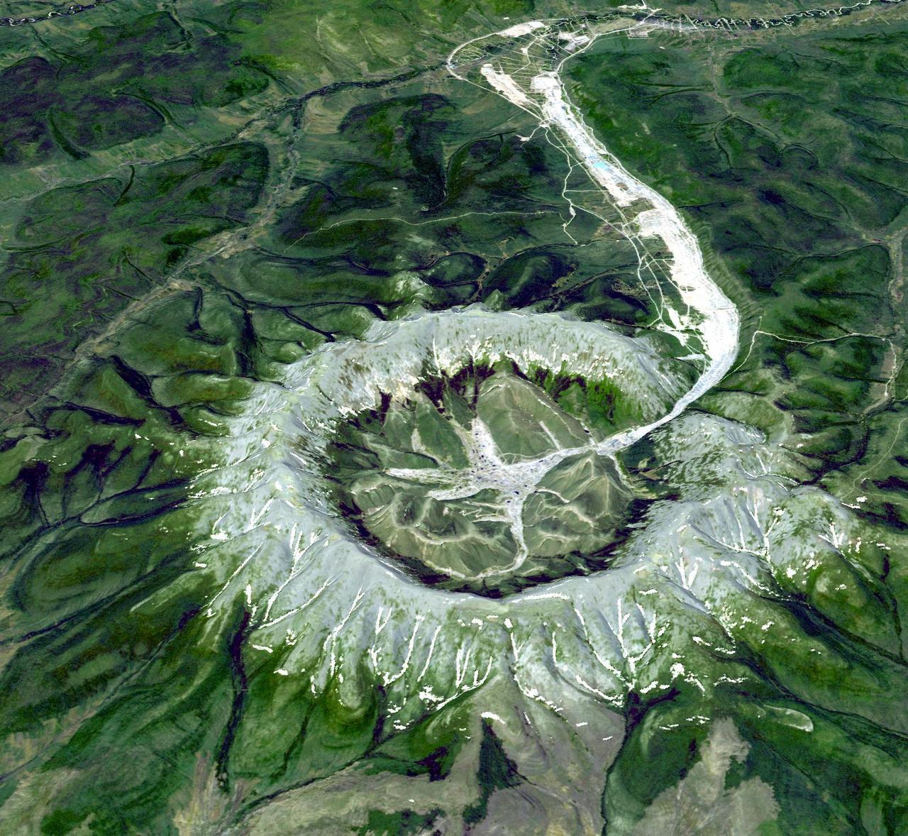 The Kondyor Massif is located in Eastern Siberia, Russia, north of the city of Khabarovsk. It is a rare form of igneous intrusion called alkaline-ultrabasic massif and it is full of rare minerals. This image is from NASA Terra satellite.