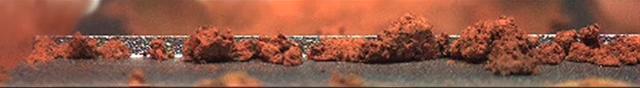 This image shows a microscopic view of fine-grained material at the tip of the Robotic Arm scoop as seen by the Robotic Arm Camera RAC aboard NASA Phoenix Mars Lander on June 20, 2008, the 26th Martian day, or sol, of the mission.