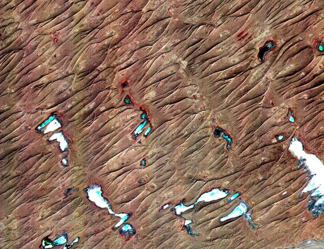 This ASTER sub-scene covers an area of 12 x 15 km in NW India in the Thar Desert. The sand dunes of the Thar Desert constantly shift and take on new shapes. Located in northwestern India and eastern Pakistan, the desert is bounded on the south by a salt marsh known as the Rann of Kutch, and on the west by the Indus River plain. About 800 kilometers long and about 490 kilometers wide, the desert's terrain is mainly rolling sandhills with scattered growths of shrub and rock outcroppings. Only about 12 to 25 centimeters of rain fall on the desert each year, and temperatures rise as high as 52 degrees Celsius. Much of the population is pastoral, raising sheep for their wool. The image is located at 24.4 degrees north latitude and 69.3 degrees east longitude. http://photojournal.jpl.nasa.gov/catalog/PIA11094