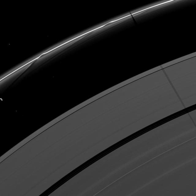 Saturn moon Janus casts a shadow on the F and A rings while the moon Prometheus, seen on the left of the image, creates a streamer-channel in the thin F ring.