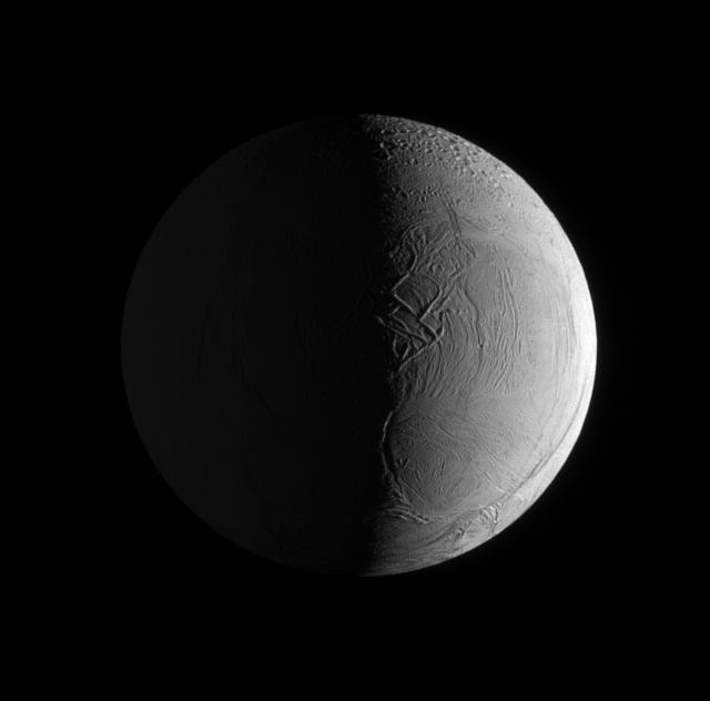 Two sources of light illuminate the textured surface of the moon Enceladus in this image taken by NASA Cassini spacecraft narrow angle camera.