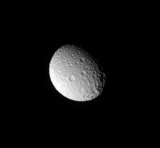 The Cassini spacecraft looks down on the north pole of Mimas and sees the moon cratered trailing hemisphere.