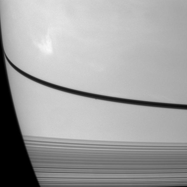 NASA Cassini Orbiter caught the shadow of the moon Prometheus as a small dark dot on Saturn just below the narrow shadow cast by the rings in the center of this image.