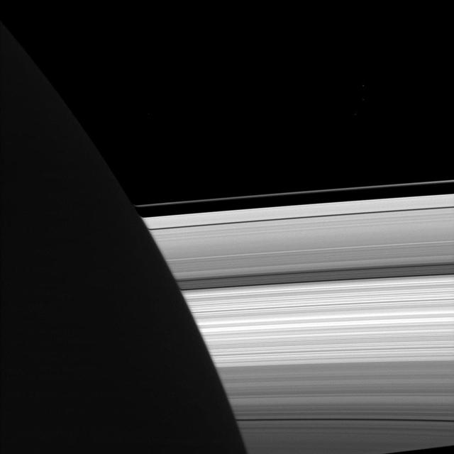 NASA Cassini spacecraft looks past the night side of Saturn, dimly lit on the left of this image by ringshine, for a subtly distorted view of the planet rings.