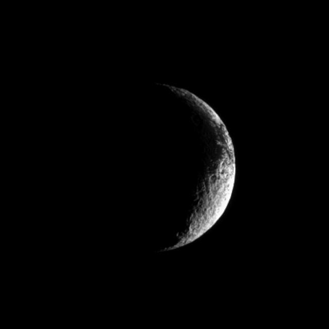 A crescent Iapetus shows, at the top right of this image from NASA Cassini spacecraft, some of the dark terrain characterizing this unusual Saturnian moon.