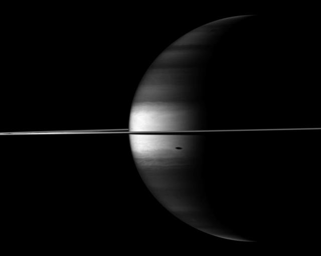 NASA Cassini spacecraft camera looks in near-infrared light at a dramatic view of Saturn, its ringplane and the shadows of a couple of its moons.