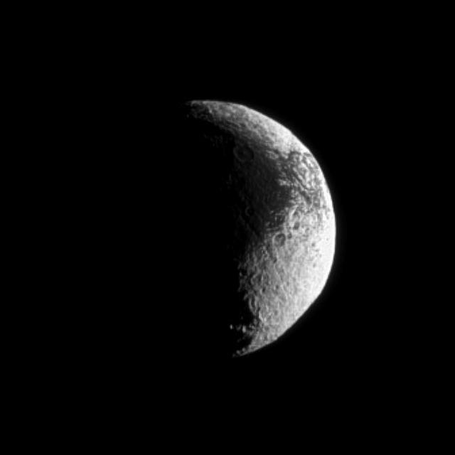 Iapetus shows off its puzzling light and dark terrain in this image captured by NASA Cassini spacecraft. Lit terrain seen here is on the Saturn-facing side of Iapetus.