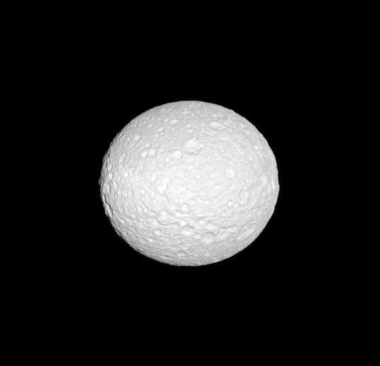 NASA Cassini spacecraft reveals the cratered surface of Mimas, a moon whose shape is flattened at the poles.