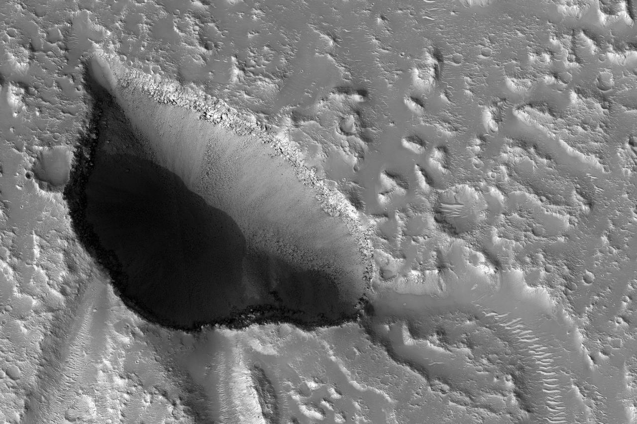 The drainages in this image are part of Hebrus Valles, an outflow channel system likely formed by catastrophic floods. Hebrus Valles is located in the plains of the Northern lowlands, just west of the Elysium volcanic region. Individual channels range from several hundred meters to several kilometers wide and form multi-threaded (anastamosing) patterns. Separating the channels are streamlined forms, whose tails point downstream and indicate that channel flow is to the north. The channels seemingly terminate in an elongated pit that is approximately 1875 meters long and 1125 meters wide. Using the shadow that the wall has cast on the floor of the pit, we can estimate that the pit is nearly 500 meters deep. The pit, which formed after the channels, exposes a bouldery layer below the dusty surface mantle and is underlain by sediments. Boulders several meters in diameter litter the slopes down into the pit. Pits such as these are of interest as possible candidate landing sites for human exploration because they might retain subsurface water ice (Schulze-Makuch et al. 2016, 6th Mars Polar Conf.) that could be utilized by future long-term human settlements. http://photojournal.jpl.nasa.gov/catalog/PIA11704