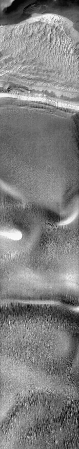 A large sand sheet with surface dune forms is located on the floor of this crater near the south pole. The polar cap rests against the southern part of the sand sheet. The dune appears bright in this daytime 2001 Mars Odyssey THEMIS IR image.