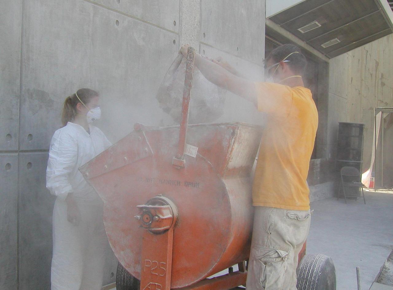 Rover team members Kim Lichtenberg left and Mike Seibert fill a mixer with powdered clay and diatomaceous earth, a combination found to offer physical properties similar to the soil where NASA rover Spirit is embedded on Mars.