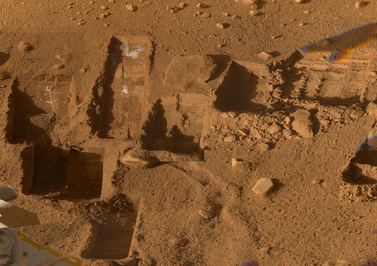 Several of the trenches dug by NASA Phoenix Mars Lander are displayed in this approximately true color mosaic of images from the lander Surface  Stereo Imager camera.