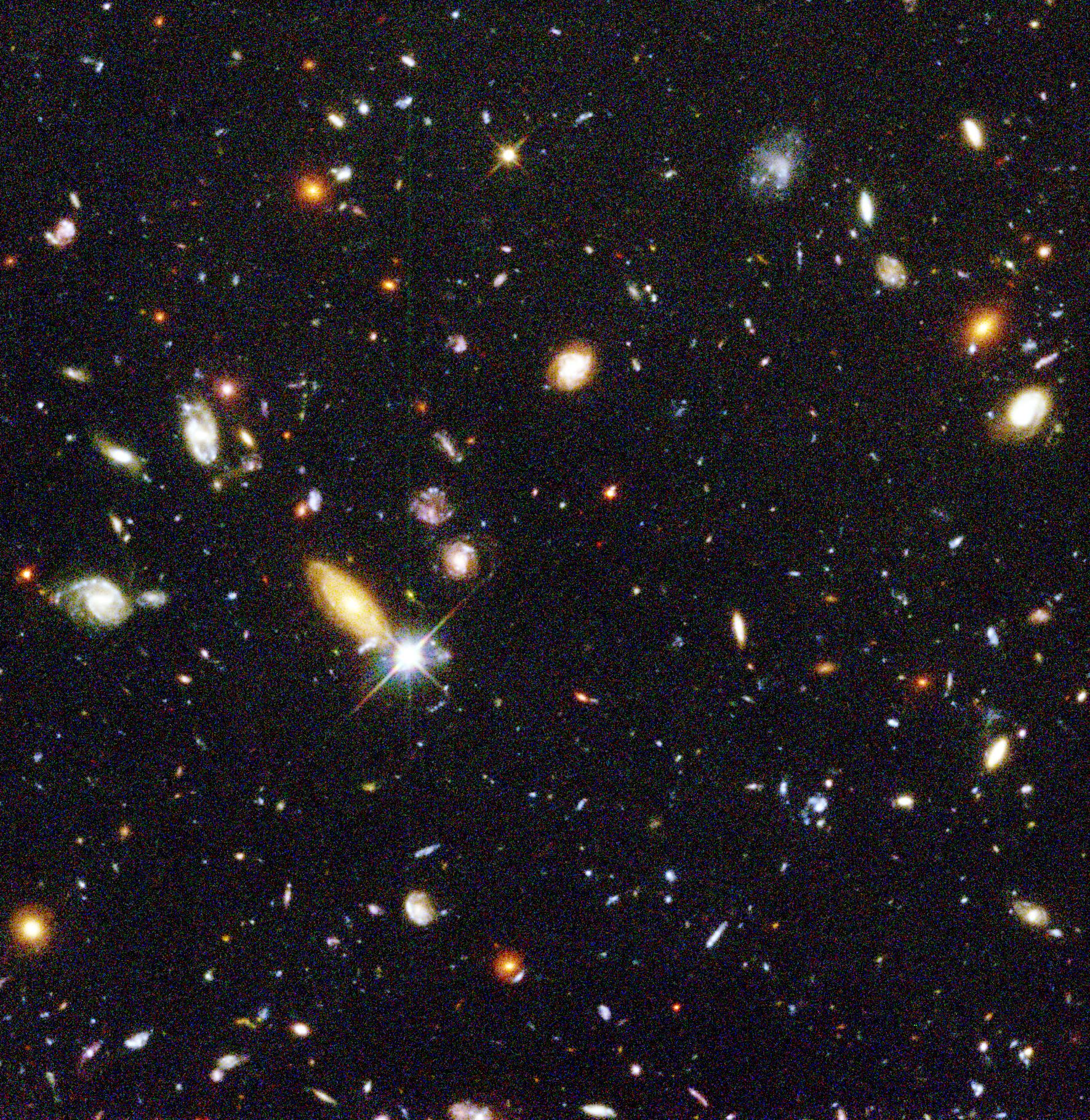 Hundreds of galaxies of all shapes and sizes shining against the dark background of space.