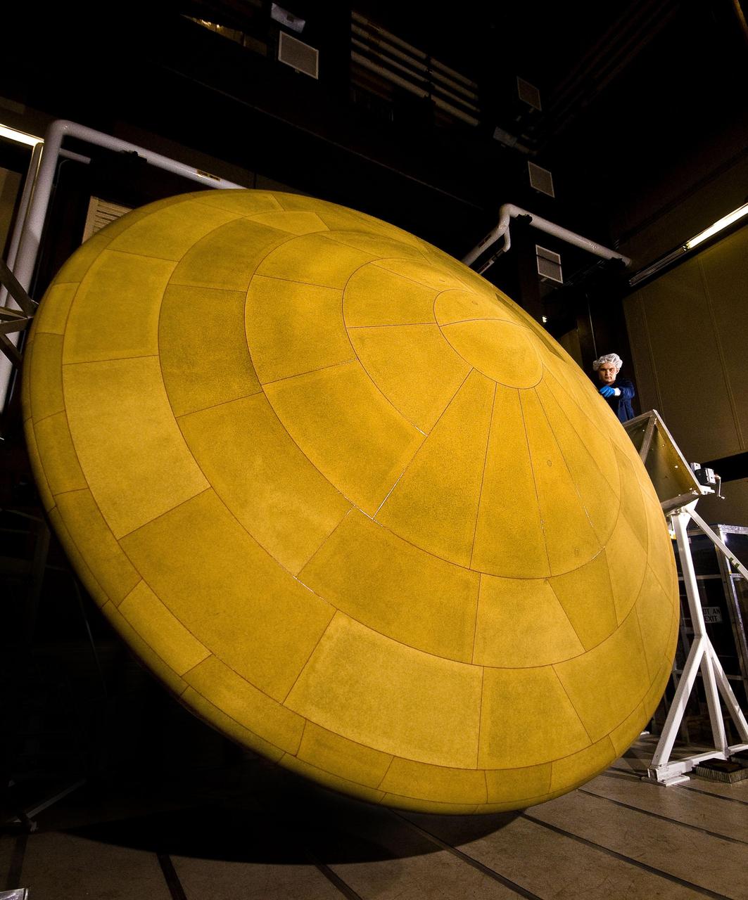 This image shows NASA Mars Science Laboratory heat shield, and a spacecraft worker at Lockheed Martin Space Systems, Denver. It is the largest heat shield ever built for descending through the atmosphere of any planet.
