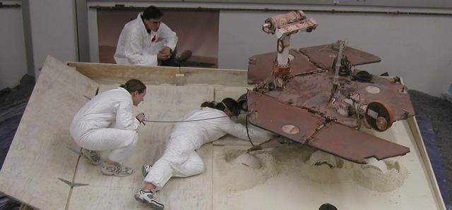 NASA Mars Exploration Rover team members prepare a testing setup for a subsequent experiment after an experiment driving the rover in a crablike motion, with all four corner wheels angled to the right.