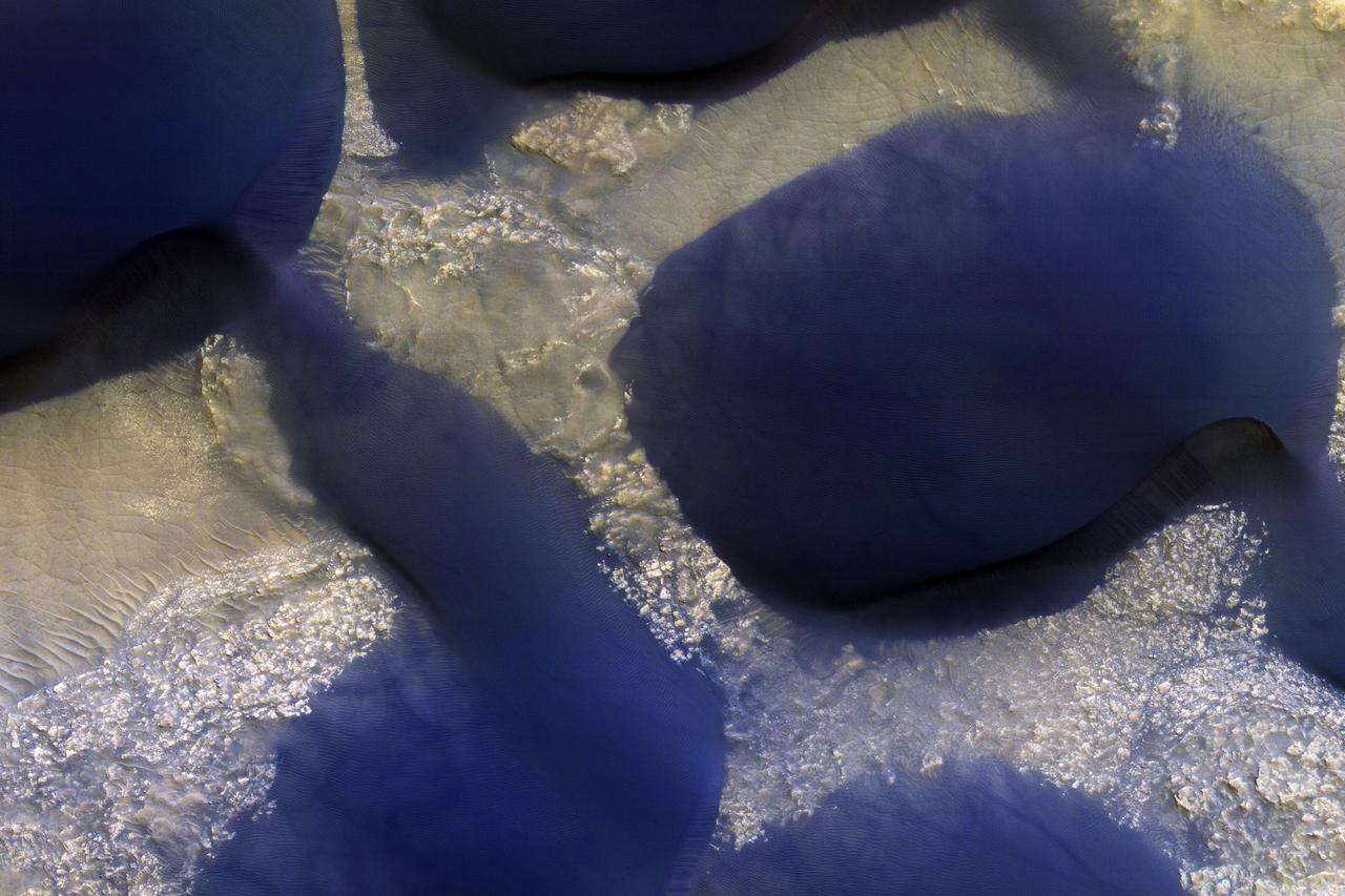 The large dark feature is a classic Martian sand dune. Most sand on Earth is made from the mineral quartz, which is white and bright. On Mars, most sand is composed of dark basalt, a volcanic rock. For this reason, dunes on Mars are darker than those on Earth. The dunes in this observation, within Wirtz Crater, are known as "barchans." The steepest slope is on the eastern (right) side, partially in shadow, and represents the direction the dune is migrating as the sand is blown and transported by the wind. Small ripples are visible on much of the dune surface. The dark streaks on the dune are tracks left by passing vortices known to us as dust devils. These raise dust off the dune, revealing a darker substrate. http://photojournal.jpl.nasa.gov/catalog/PIA12289