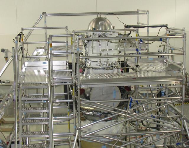 A scaffolding structure built around NASA Wide-field Infrared Survey Explorer allows engineers to freeze its hydrogen coolant. The WISE infrared instrument is kept extremely cold by a bottle-like tank filled with frozen hydrogen, called the cryostat.