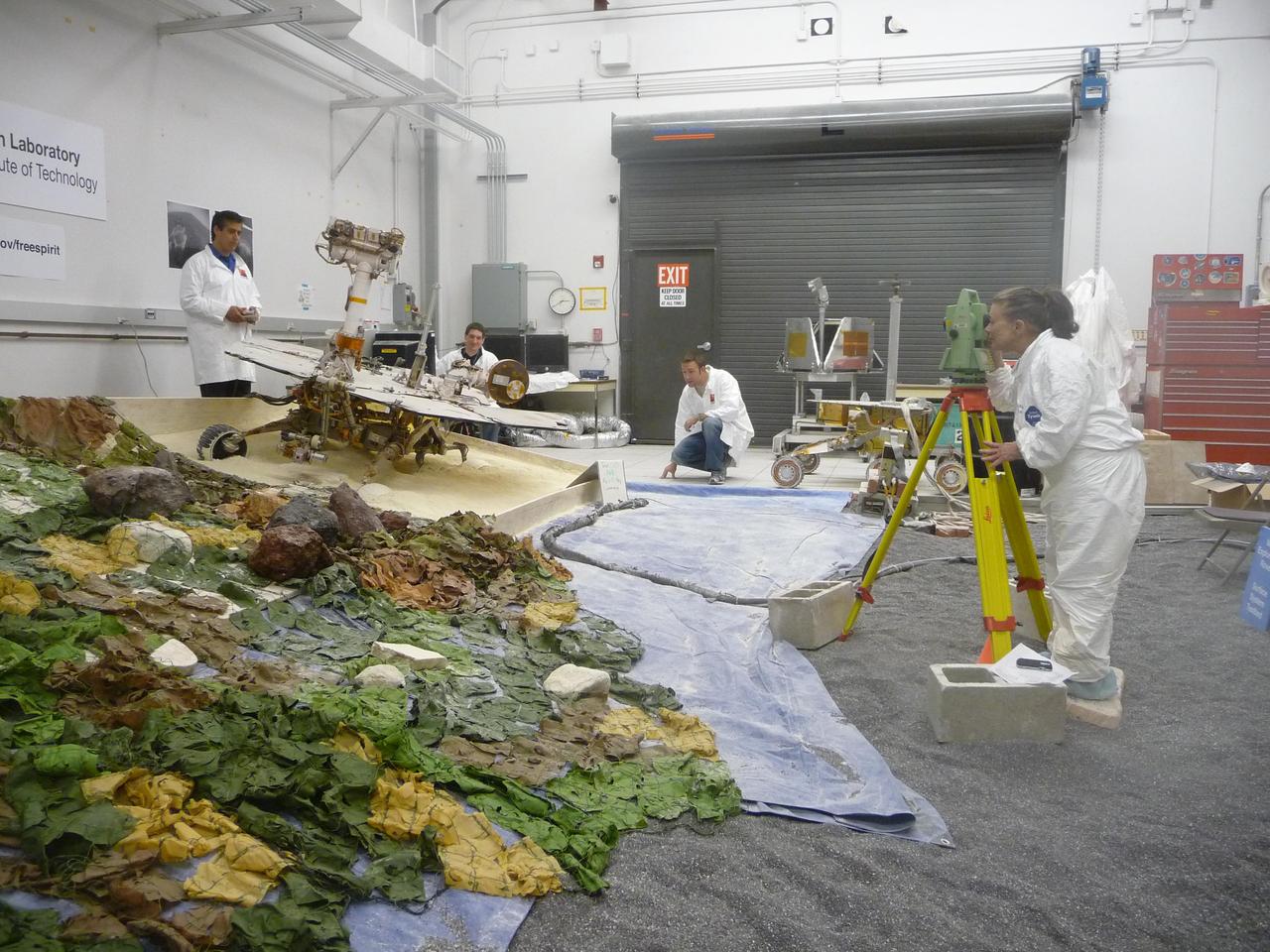 Rover-team members at NASA Jet Propulsion Laboratory, Pasadena, Calif., check slight movements by a test rover during tests simulating the challenge of getting NASA Mars Exploration Rover Spirit out of a sand trap on Mars.