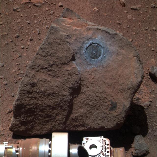 Perched on a rippled Martian plain, a dark rock not much bigger than a basketball was the target of interest for NASA Opportunity during the past two months; Opportunity rock abrasion tool brushed dust out of the circular area.