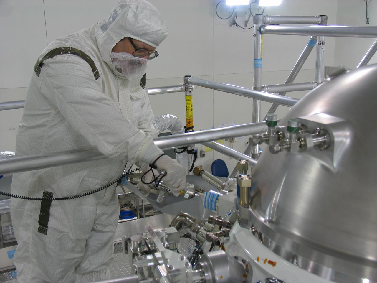 An engineer loads hydrogen gas into the Wide-Field Infrared Survey Explorer in a clean room at the Vandenberg Air Force Base, Calif. The hydrogen is cooled and frozen inside a Thermos-like bottle, called the cryostat, which keeps the science instrument