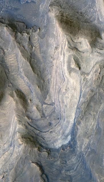 Layers of rock exposed in the lower portion of a tall mound near the center of Gale Crater on Mars exhibit variations in layer thickness and range between dark and light tones in this image taken by NASA Mars Reconnaissance Orbiter.