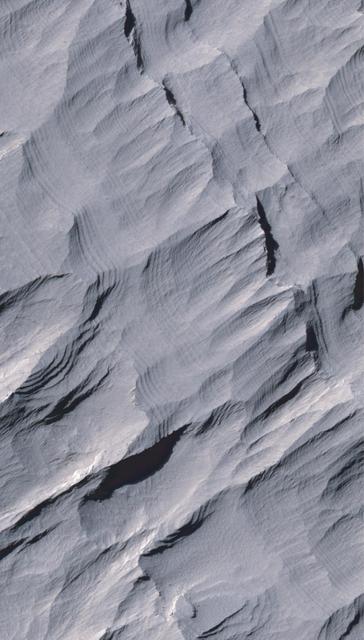 Layers of rock in the upper portion of a tall mound near the center of Gale Crater on Mars exhibit a regular thickness of several meters in this image taken by NASA Mars Reconnaissance Orbiter.