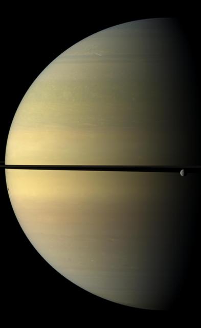 Saturn, stately and resplendent in this natural color view taken by NASA Cassini spacecraft, dwarfs the icy moon Rhea. Rhea orbits beyond the rings on the right of the image. Tethys shadow is visible on the planet on the left of the image.