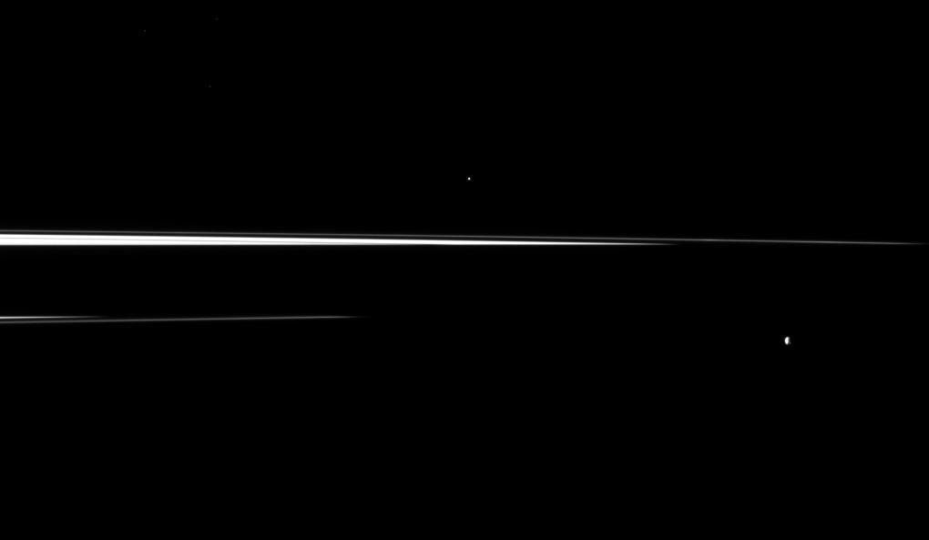 Saturn shadow interrupts the planet rings, leaving just thin slivers of the rings visible in this image, which shows a pair of the planet small moons. Helene is in the center top of the image, Epimetheus is in the lower right.