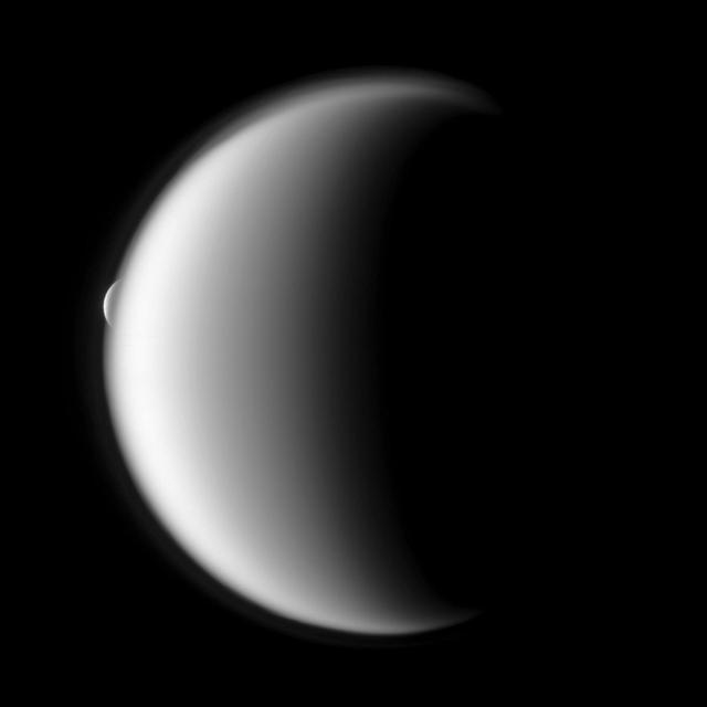 Rhea emerges after being occulted by the larger moon Titan in this image taken by NASA Cassini spacecraft.
