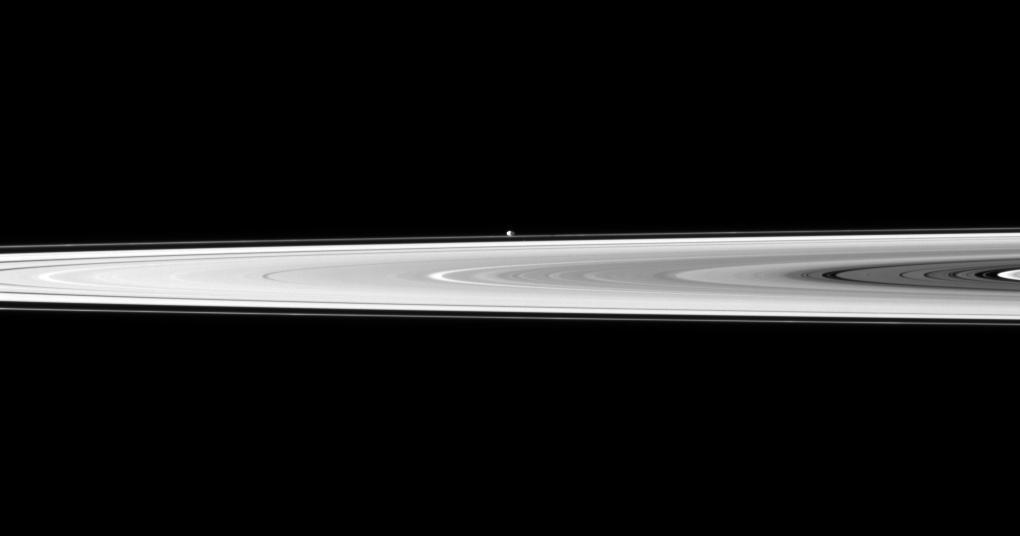 The tiny moon Pandora appears beyond the bright disk of Saturn rings in this image taken by NASA Cassini spacecraft. Pandora orbits outside the F ring and, in this image, is farther from Cassini than the rings are.