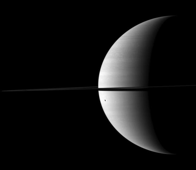 Dione shadow is elongated as it is cast onto the round shape of Saturn in this image taken by NASA Cassini spacecraft. The moon is not visible here. This view looks toward the northern, sunlit side of the rings from just above the ringplane.
