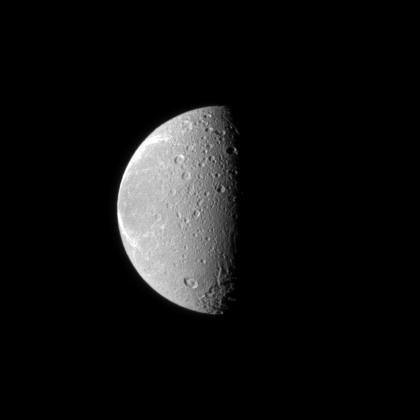 The tortured terrain of Saturn moon Dione is documented in this NASA Cassini spacecraft image. The wispy fractures on the moon trailing hemisphere can be seen on the left, and cratered terrain on the moon anti-Saturn side dominates the center.