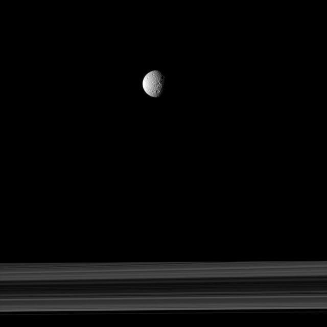 The cratered moon Mimas appears as if it has been hung like an ornament above Saturn rings in this image taken by NASA Cassini spacecraft.