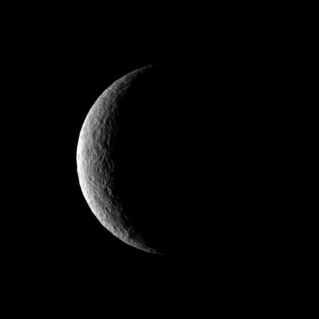 NASA Cassini spacecraft captures a crescent of crater-covered surface on the moon Rhea. Lit terrain seen here is on the trailing hemisphere of Rhea. North on Rhea is up.