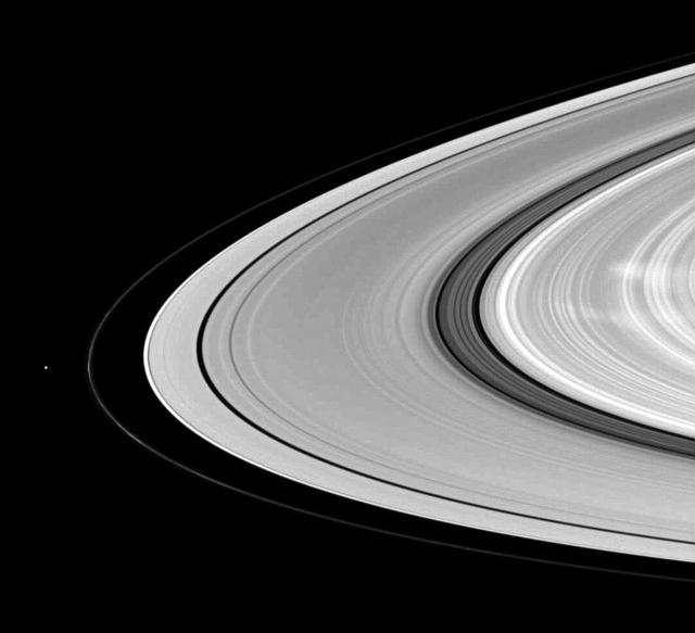 Saturn moon Pandora shares the stage with ghostly B ring spokes in this NASA Cassini spacecraft scene. Pandora is on the left. The spokes are the radial markings visible on the right of the image.