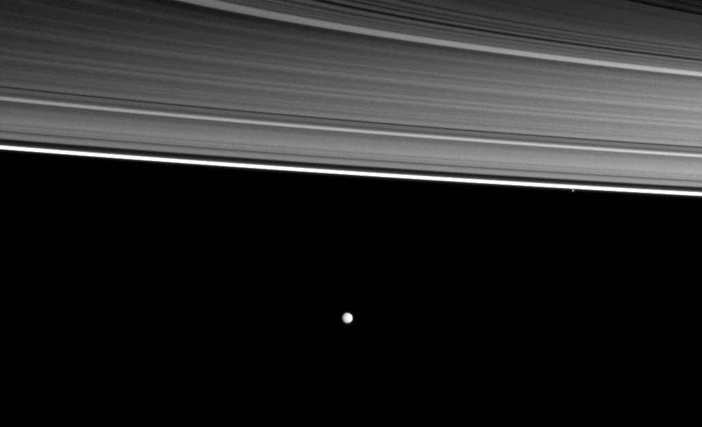 Two of Saturn moons orbit beyond four of the planet rings in this image from NASA Cassini spacecraft. From the top right of the picture are the C, B , A, and thin F rings, the small moon Pandora and, near the middle of the image, the moon Enceladus.