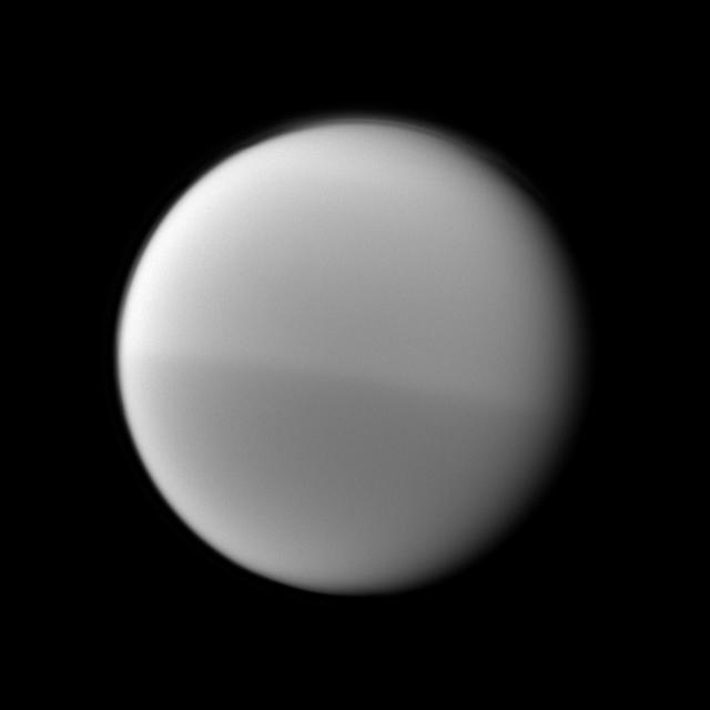 NASA Cassini spacecraft records Titan seasonal hemispheric dichotomy, with the moon northern half appearing slightly lighter than the southern half in this image.