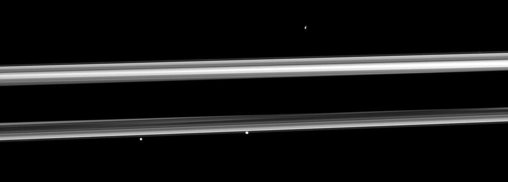 Three of Saturn small moons straddle the rings in this image captured by NASA Cassini spacecraft. From left to right are Pandora, Prometheus and, near the top right, Epimetheus.
