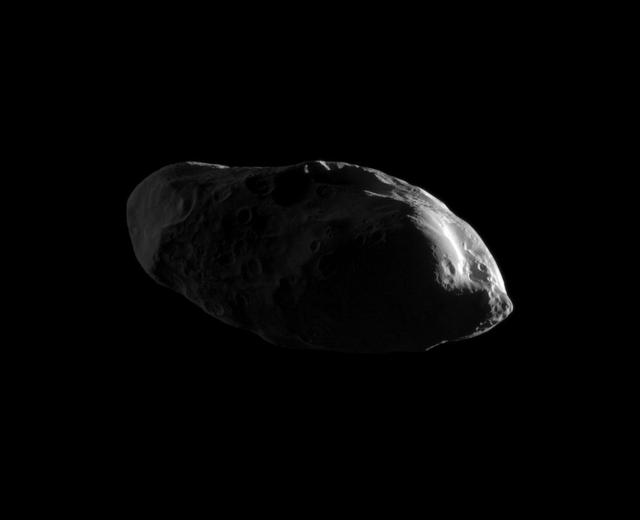Appearing like eyes on a potato, craters cover the dimly lit surface of the moon Prometheus in this high-resolution image from NASA Cassini spacecraft early 2010 flyby.