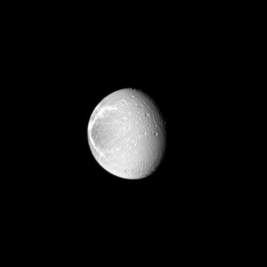 Sunlight highlights the bright, wispy features on the trailing hemisphere of Saturn moon Dione as seen by NASA Cassini spacecraft. These wispy features are a system of braided canyons with bright walls caused by fractures.
