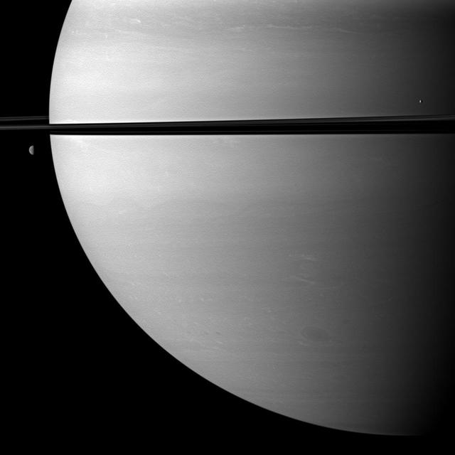 Two moons orbit serenely before Saturn while large storms churn through the planet southern hemisphere in this image taken by NASA Cassini spacecraft. The moon Mimas is on the right. Dione is on the left.