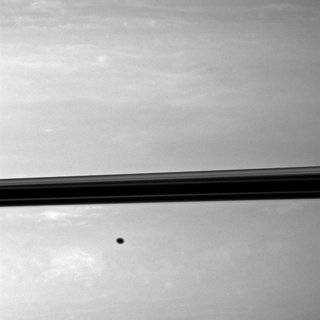 Appearing like a freckle on the face of Saturn, a shadow from the moon Enceladus blemishes the planet just below the ringplane in this NASA Cassini spacecraft image.