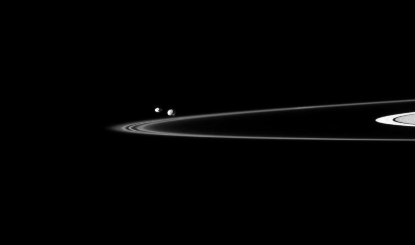 Two of Saturn small moons can be seen orbiting beyond the planet thin F ring in this image captured by NASA Cassini spacecraft. Pandora is on the left, and Epimetheus is on the right.