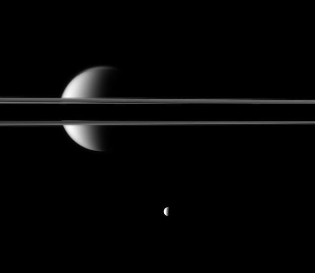 Saturn rings, partially darkened by the planet shadow, cut a striking figure before Saturn largest moon, Titan. The moon Mimas is near the bottom of this image taken by NASA Cassini spacecraft.