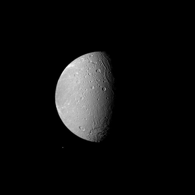 Saturn moon Dione dwarfs the moon Telesto in this image captured by NASA Cassini spacecraft image. Dione is the fourth largest of Saturn moons, and it dominates this view. Tiny Telesto can be seen below and to the left of Dione.